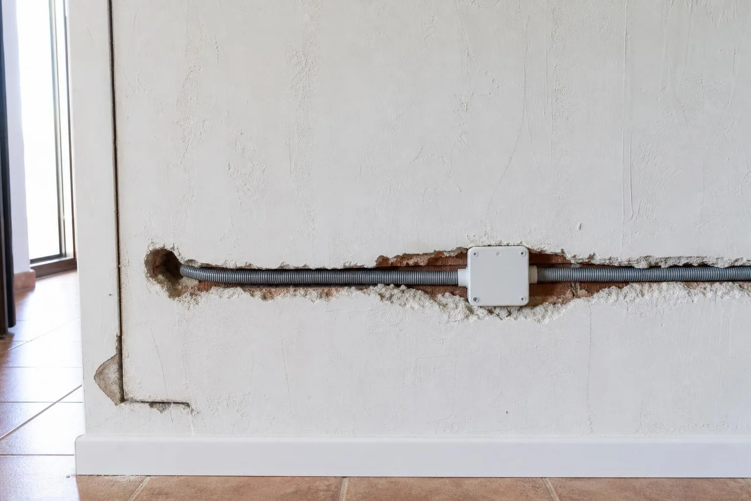 Roza abierta en la pared con cable nuevo y caja de registro
