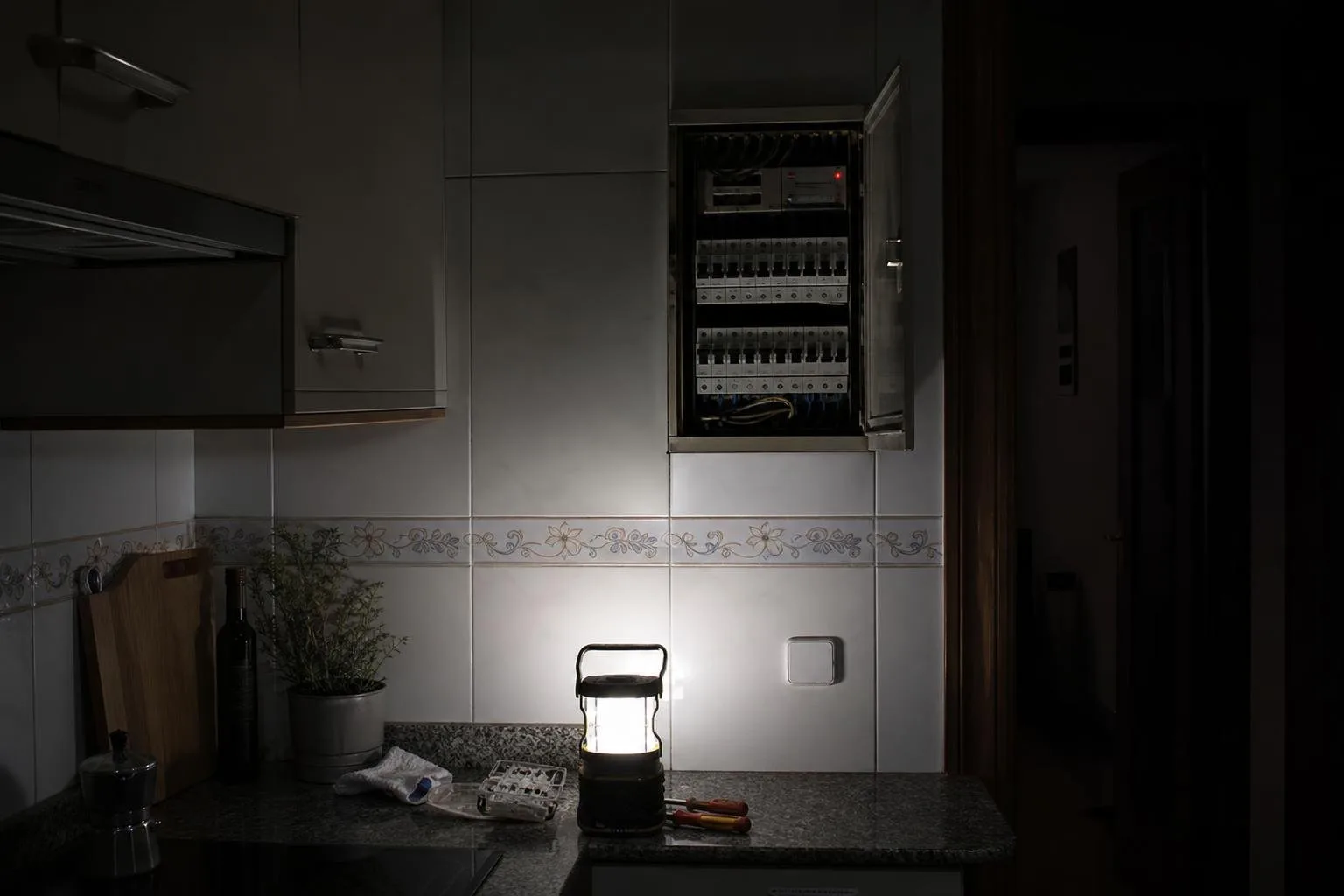 Cocina a oscuras con el cuadro eléctrico abierto e iluminado con una lámpara de trabajo